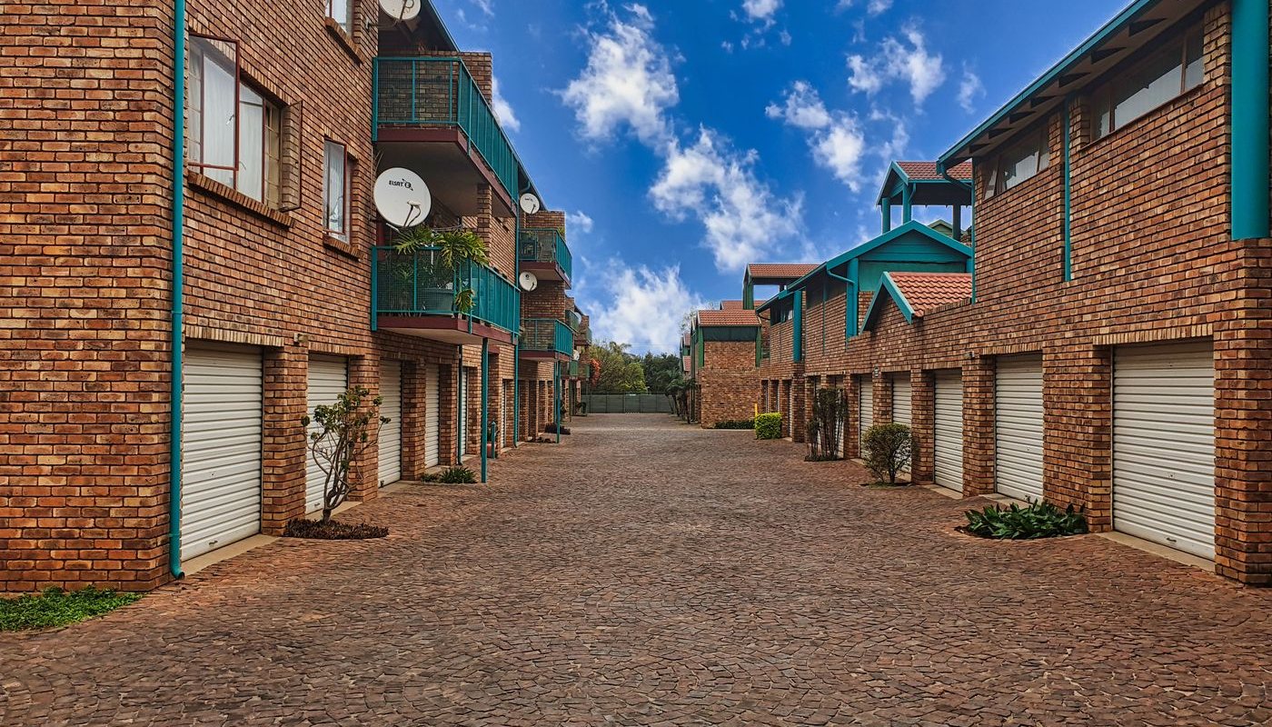 Brick apartment complex with balconies under a blue sky