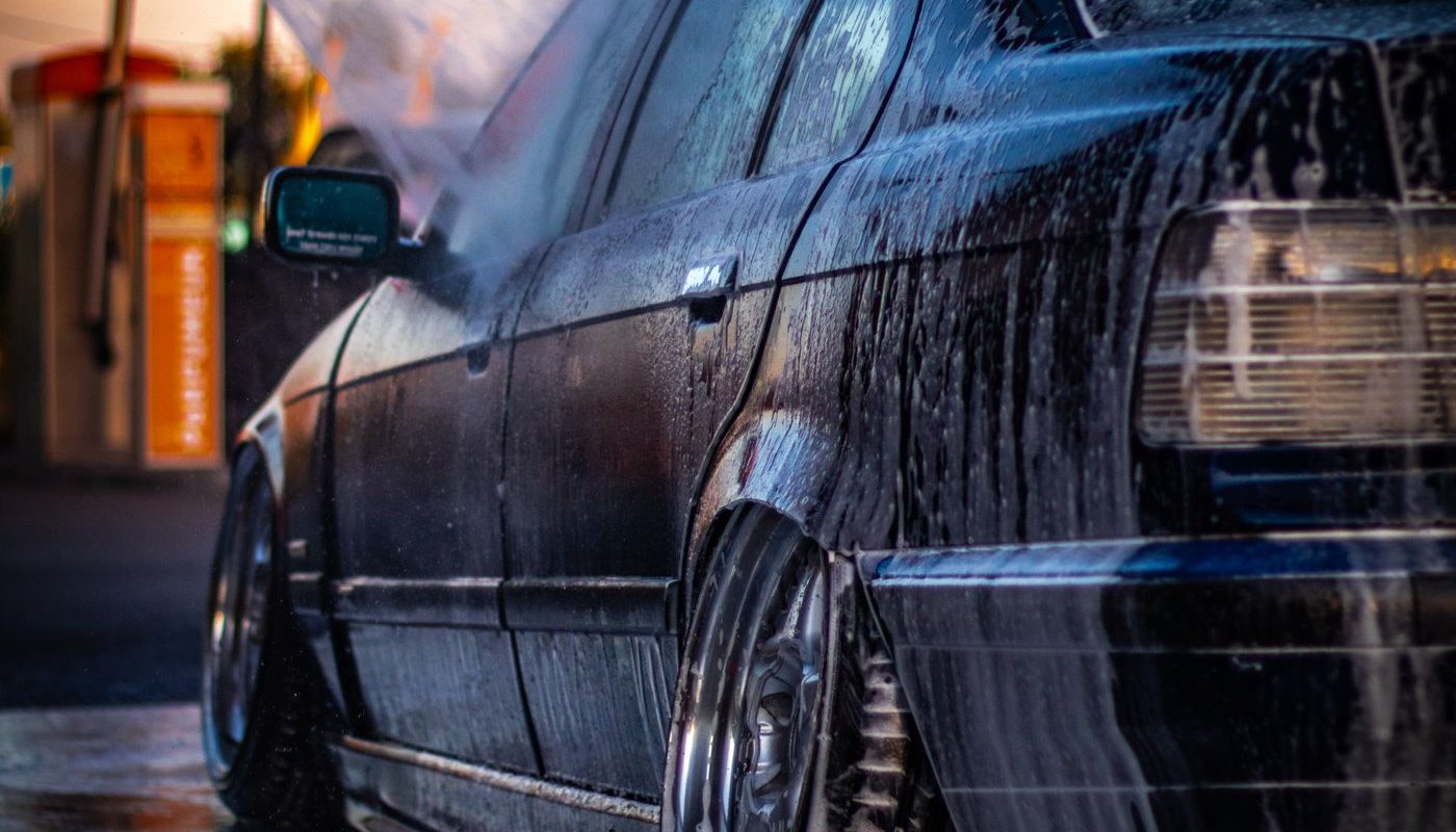 Dark car covered in soap at a car wash