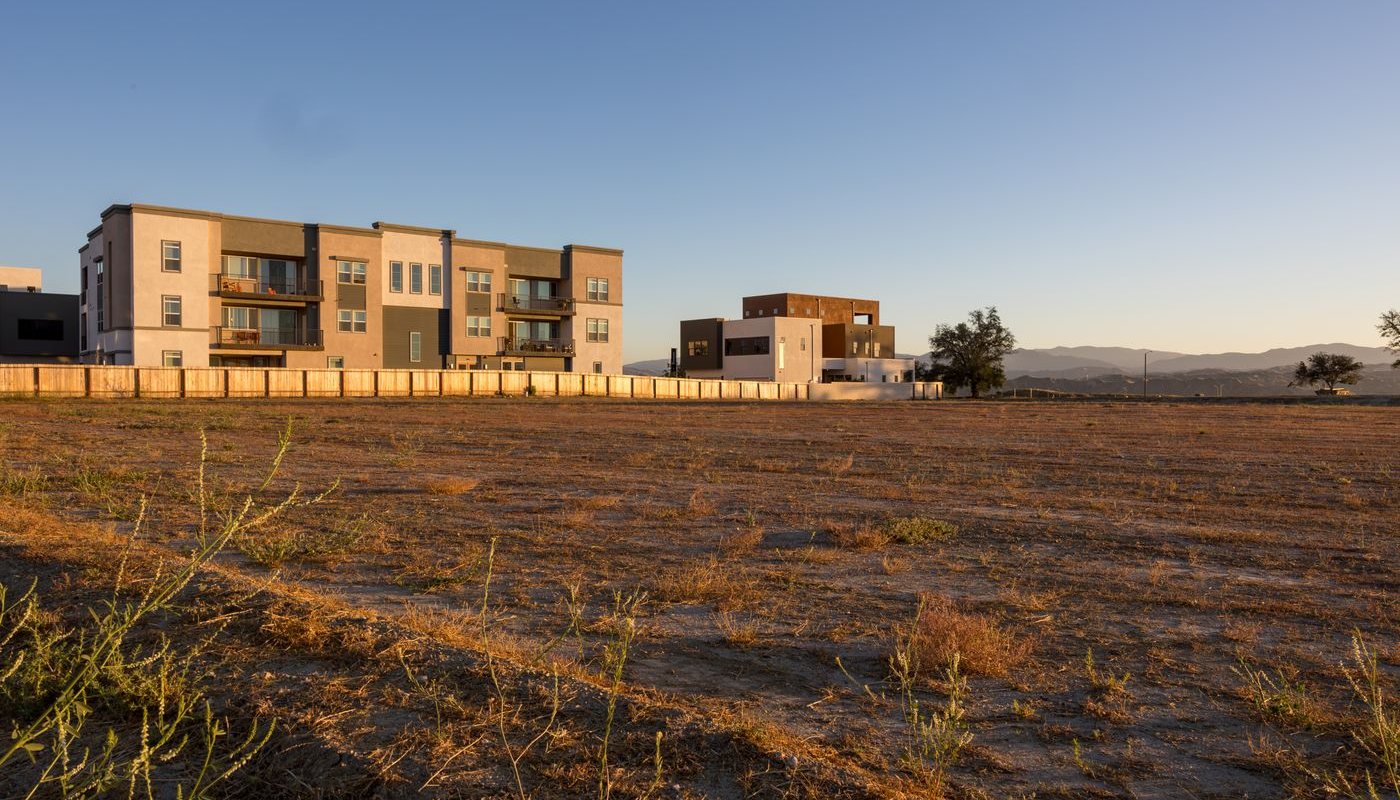 Open field at sunset with modern buildings in the background