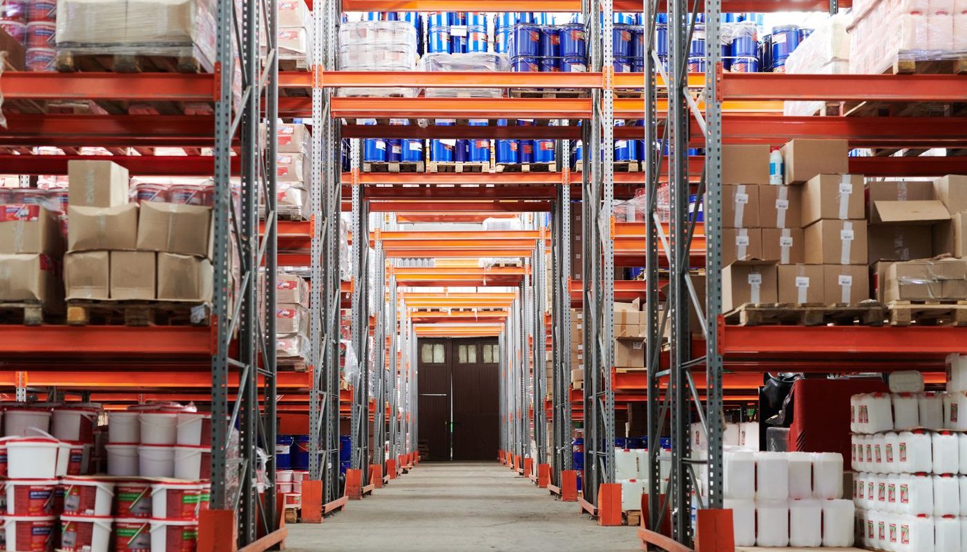 Warehouse aisle with tall orange racking and stacked pallets