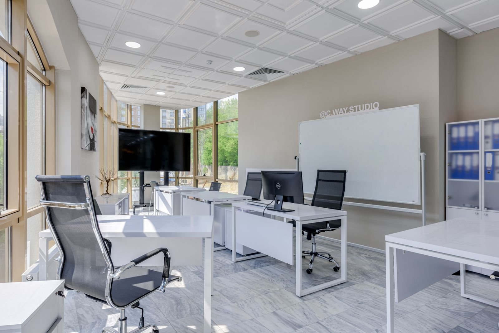 Bright modern office with desks, a whiteboard and large windows