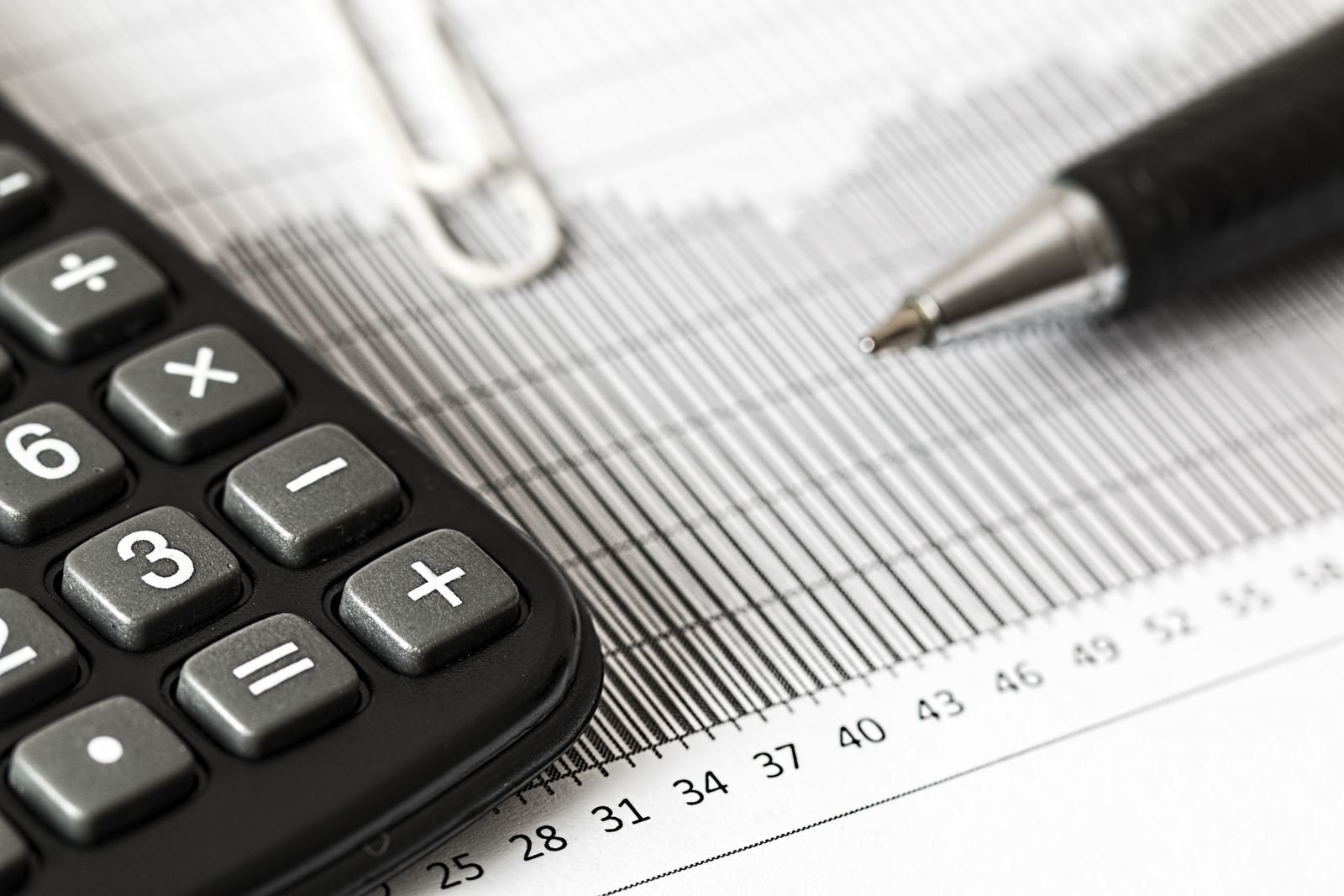 Calculator and pen resting on a printed bar chart