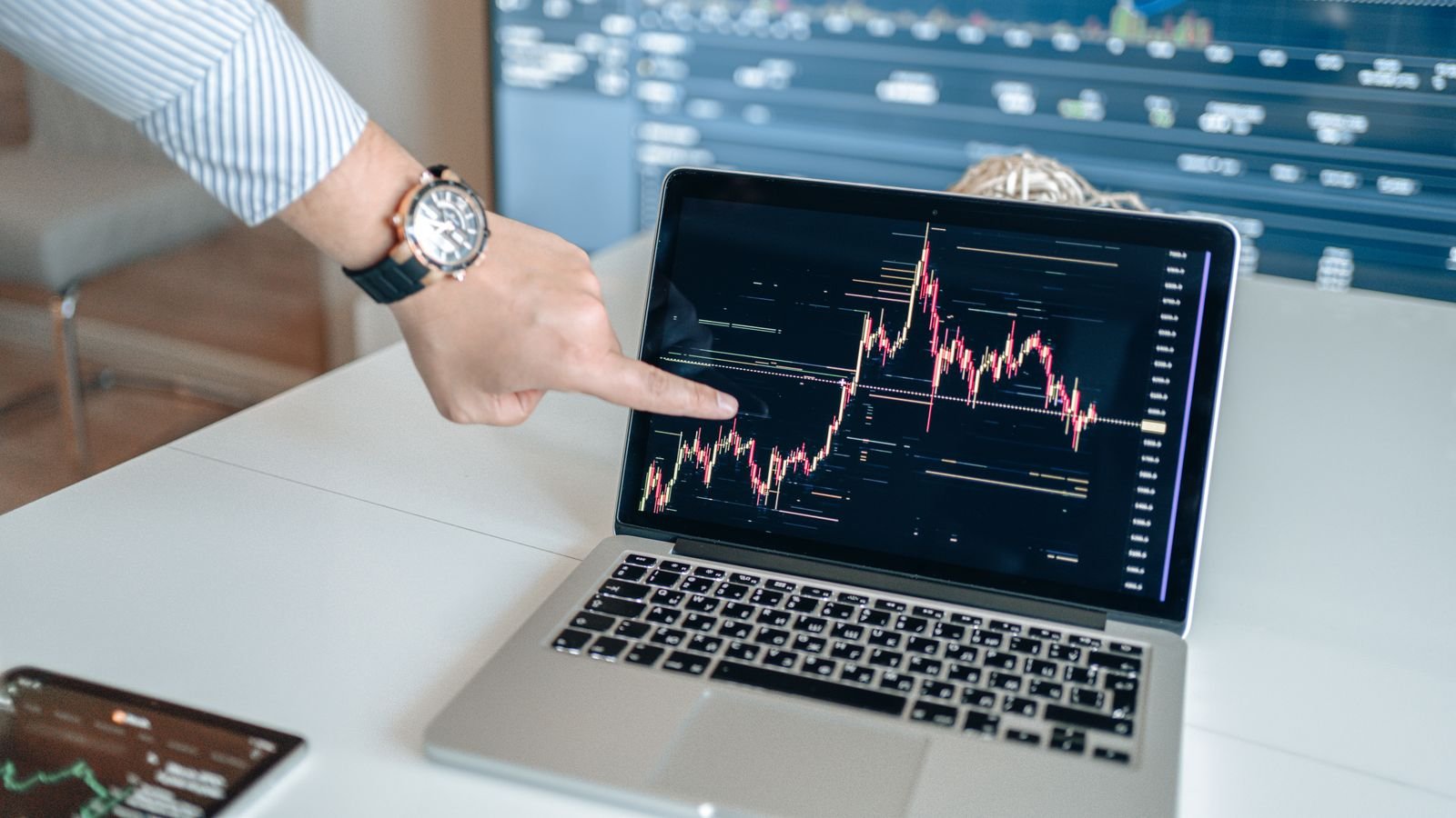 Person pointing at a chart on a laptop screen during an analysis