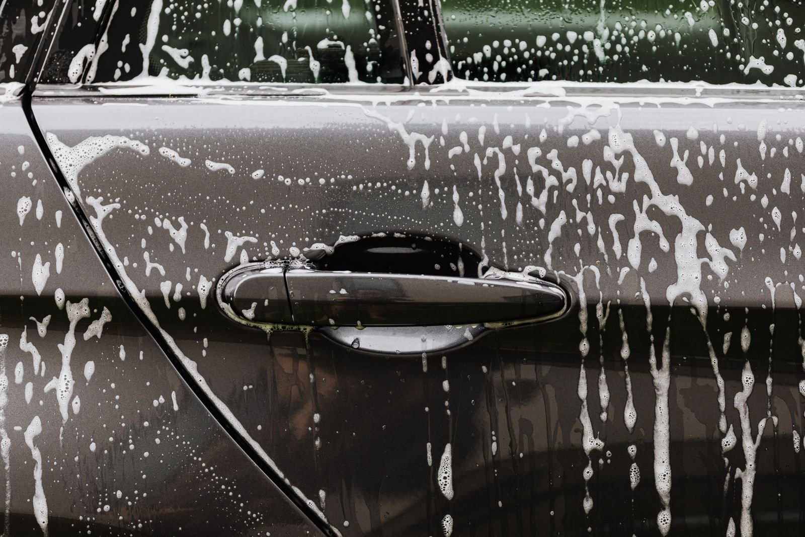 Soap suds running down the door of a dark car