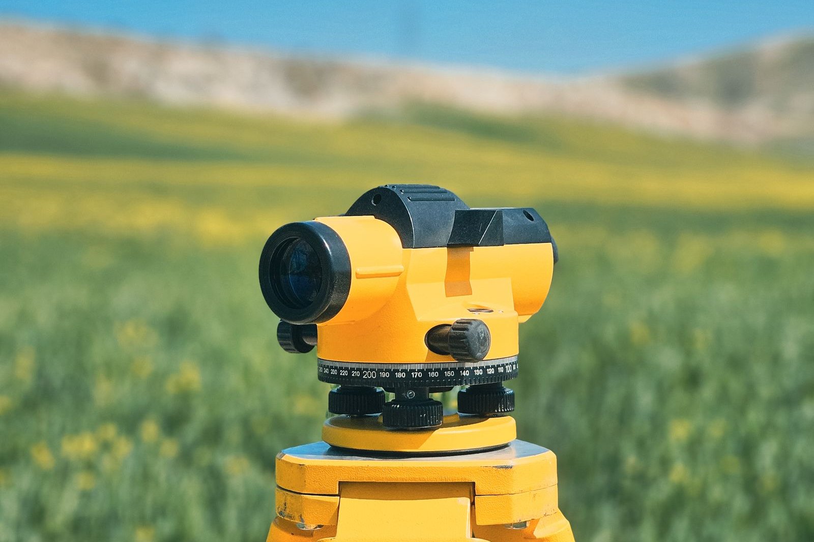 Yellow survey level on a tripod in a green field