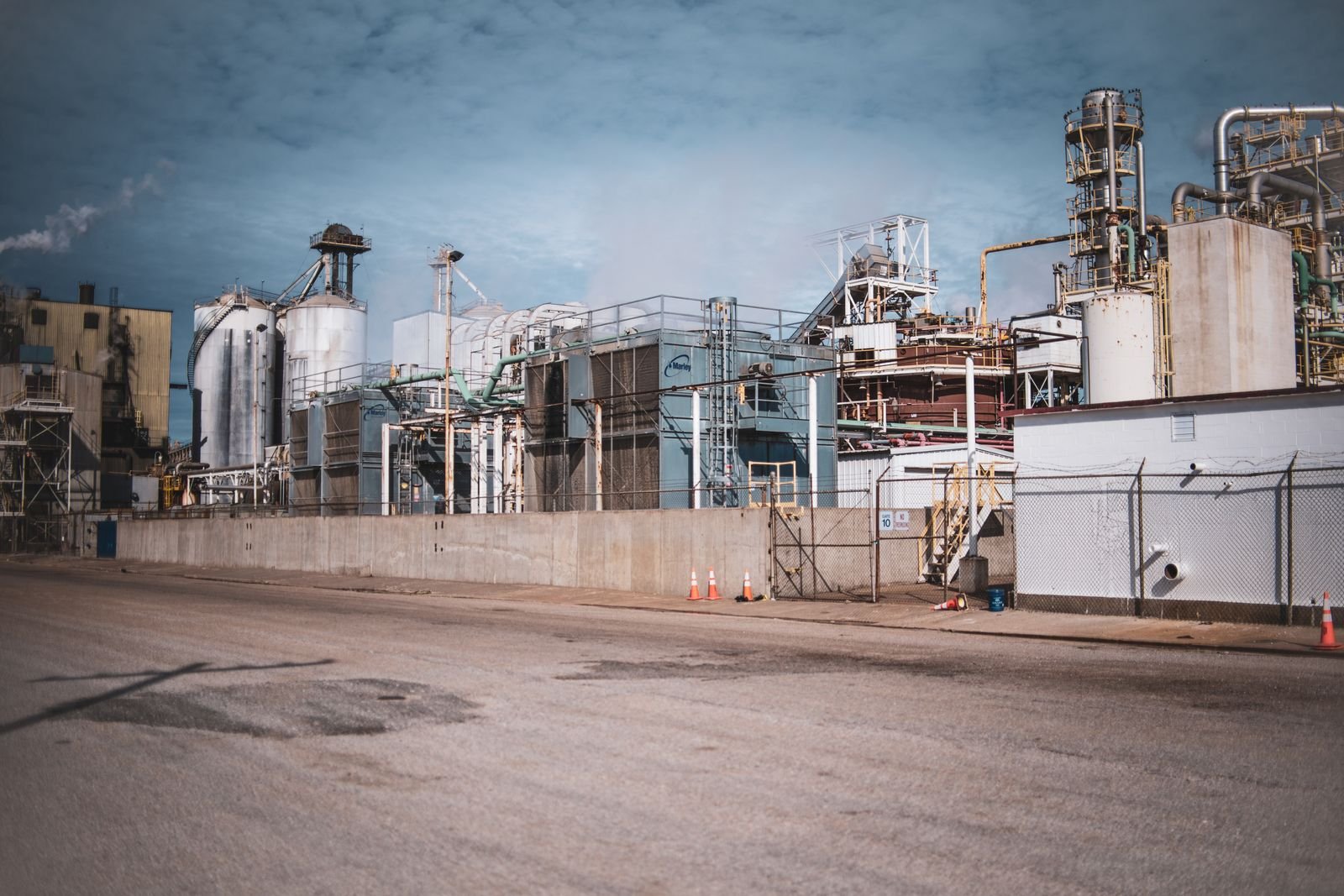 Industrial plant with silos and pipework beside an empty road