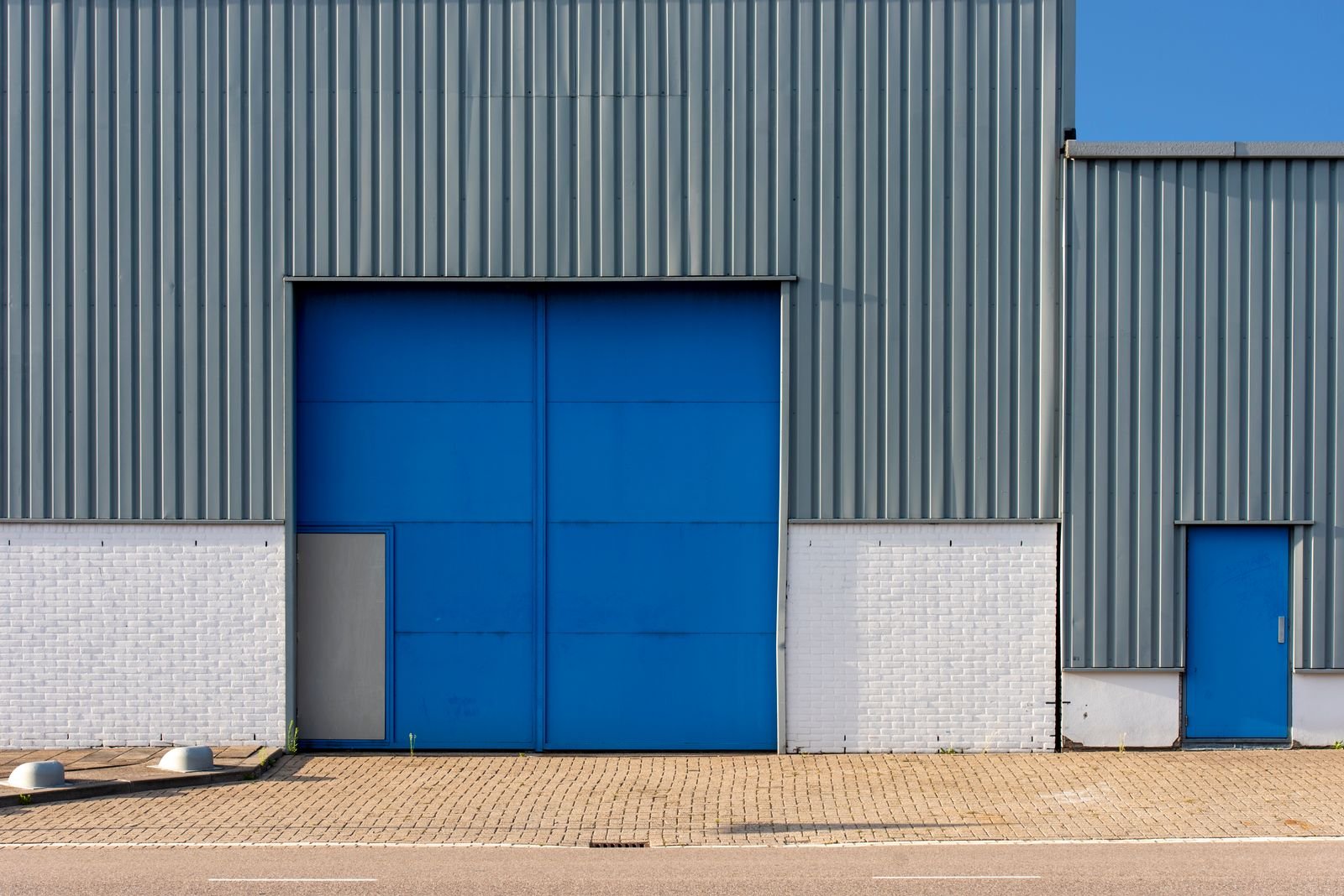 Grey metal-clad warehouse with a large blue loading door