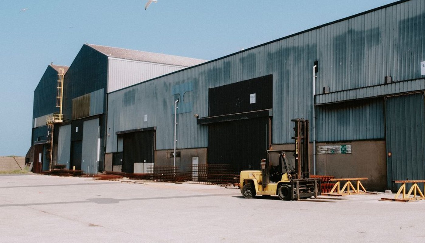 Large industrial warehouse building with loading doors and a forklift