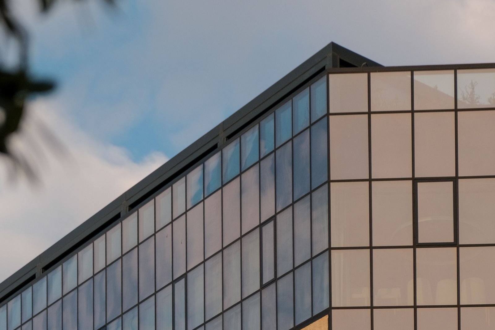 Corner of a modern glass and panel building against a soft evening sky