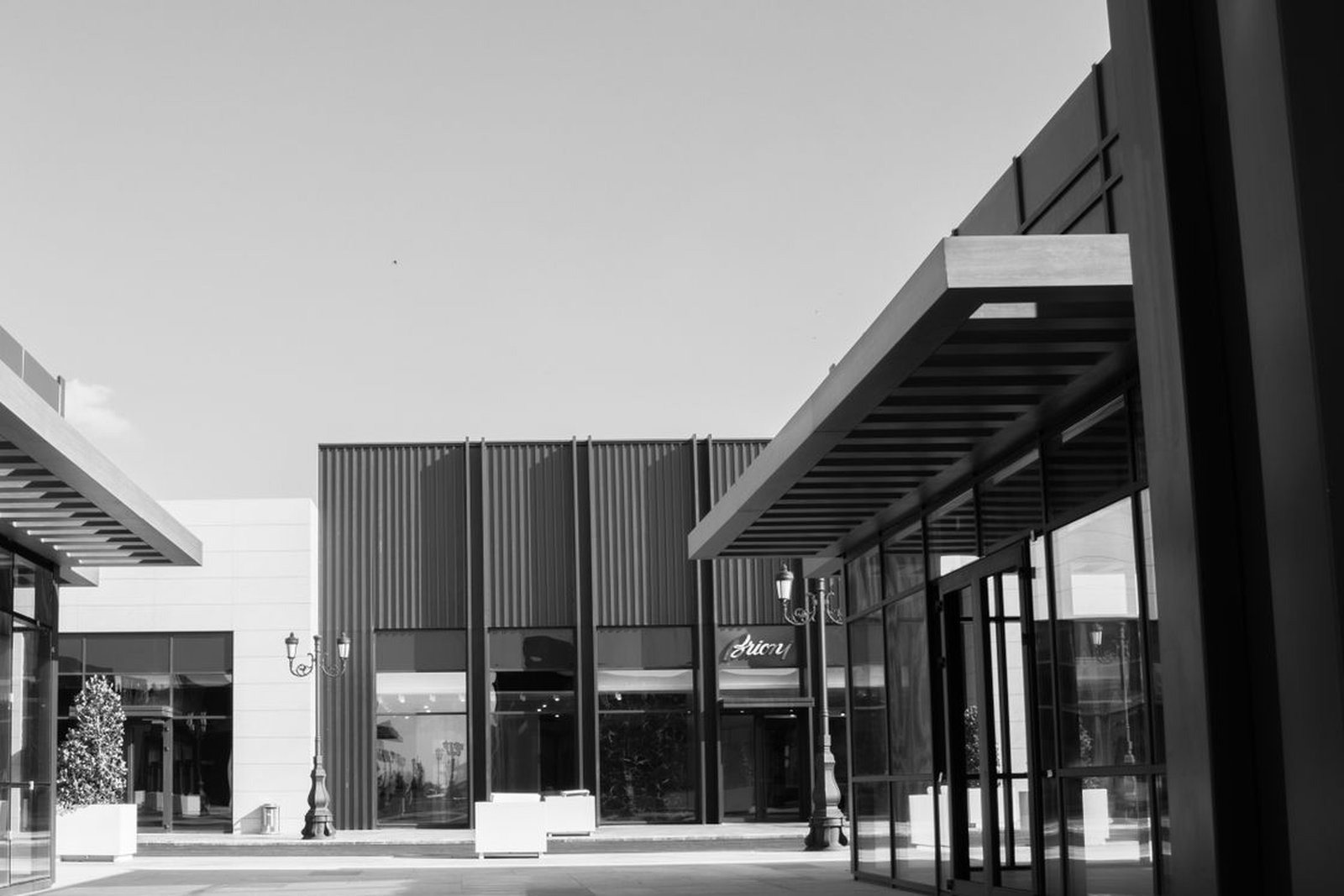 Black and white view of modern retail storefronts with covered walkways