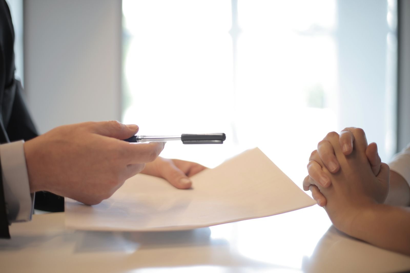 Person handing a lease document and pen across a meeting table