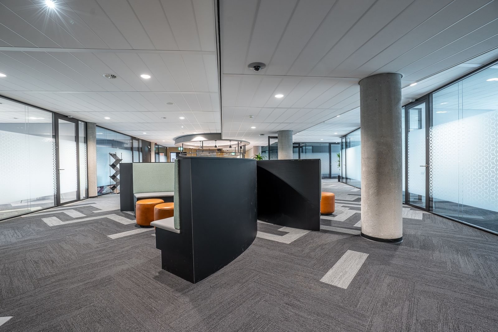 Empty open-plan office floor with glass partitions and a concrete column