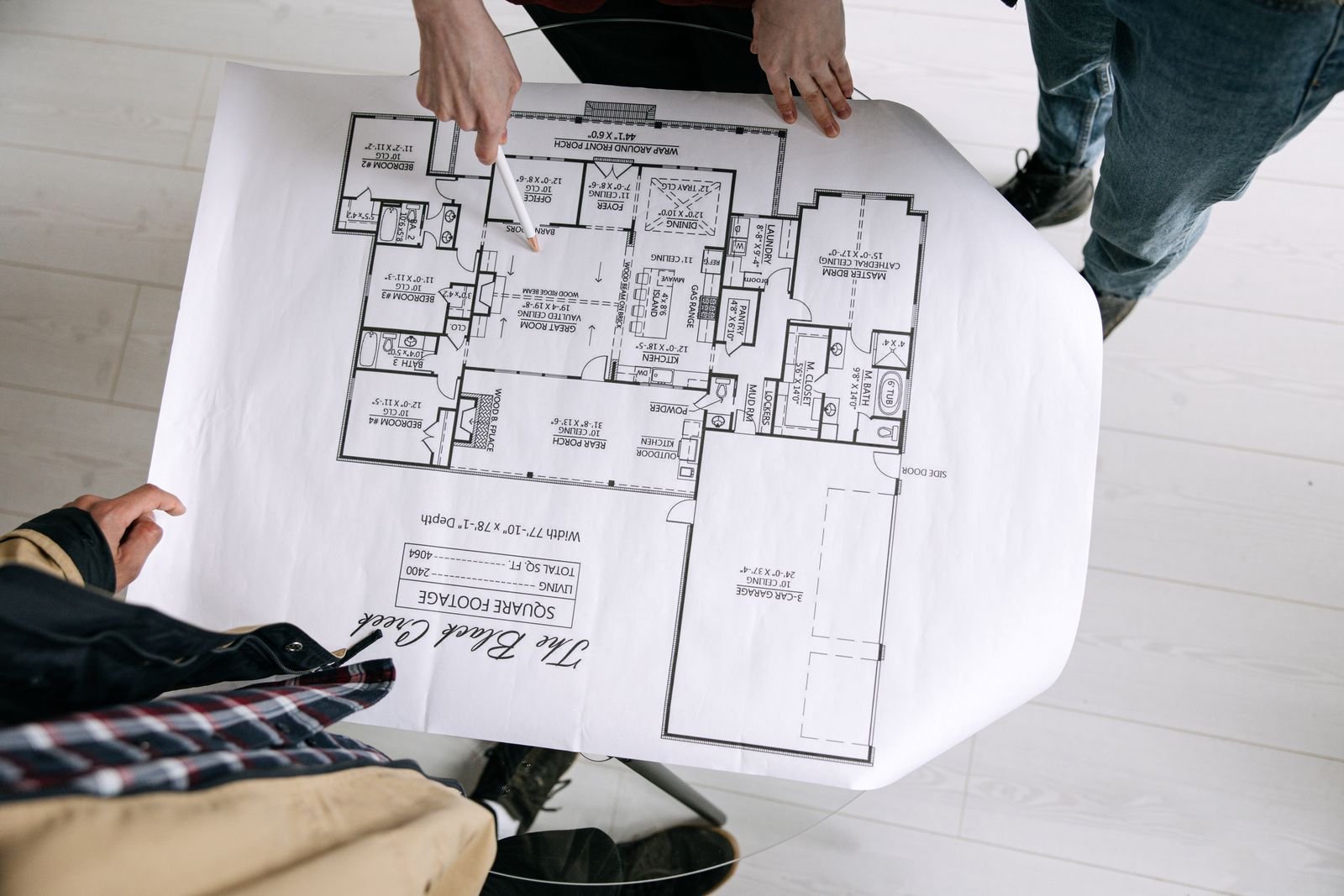 Overhead view of people examining a large floor plan drawing