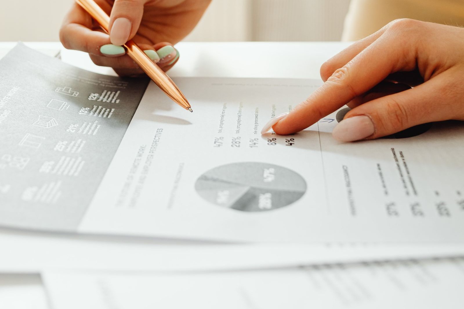 Hands pointing at printed charts and financial documents on a desk