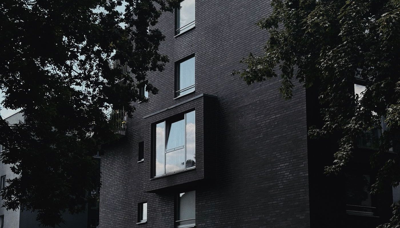 Dark brick apartment building surrounded by trees