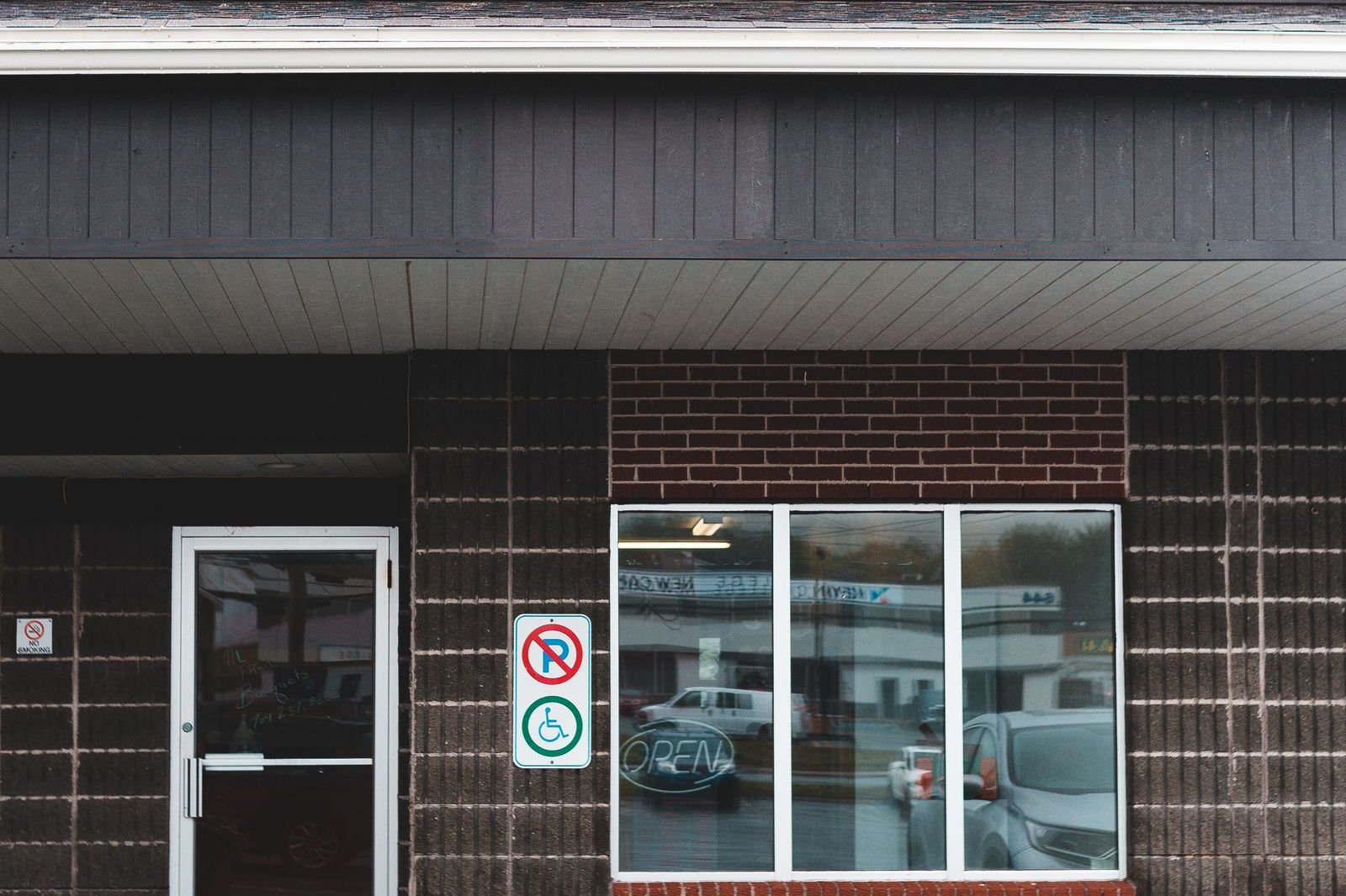 Small brick and dark-clad commercial building with a glass door and window