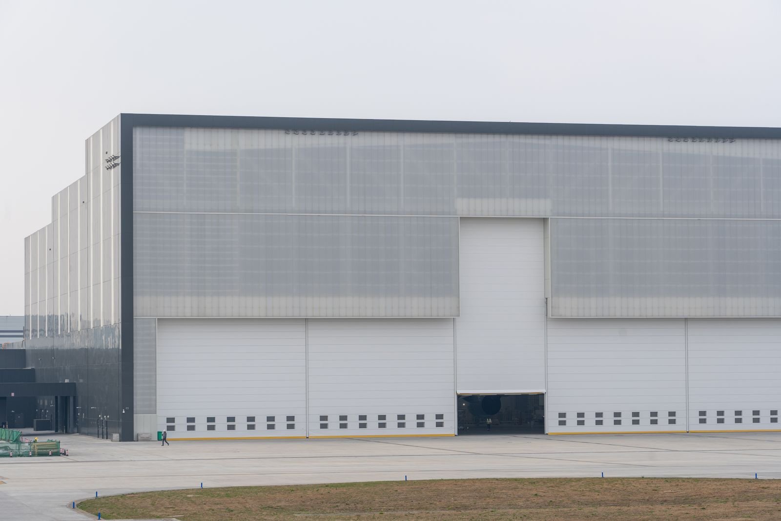 Large grey industrial building with big loading doors on a flat site