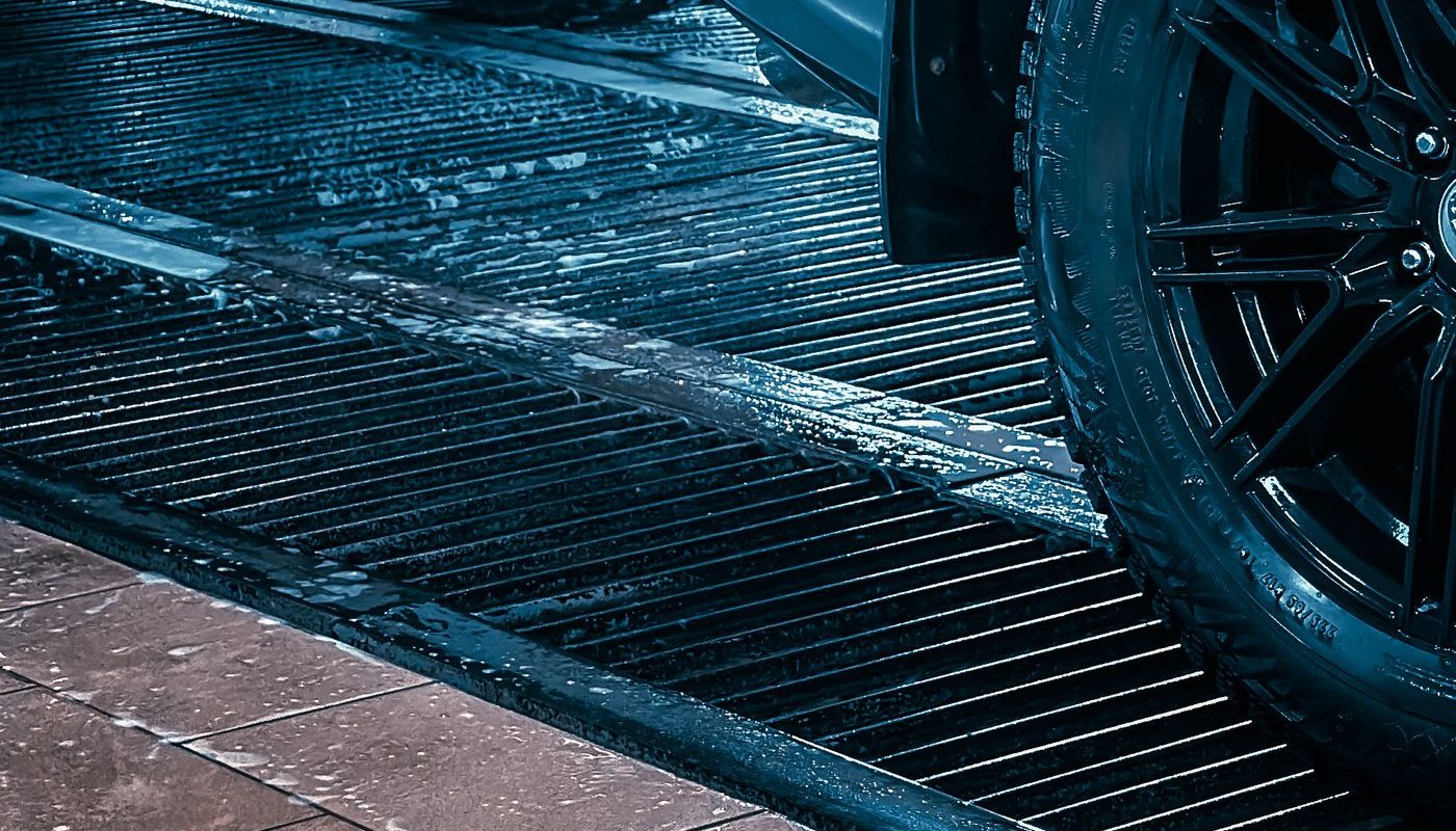 Wet drainage grates and a tyre inside a car wash bay