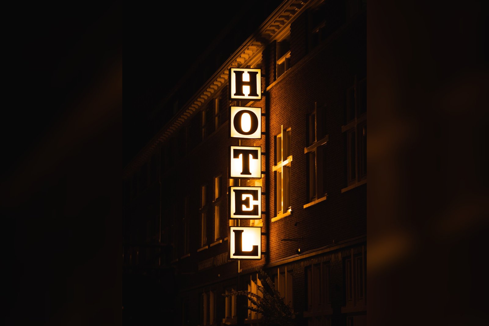 Illuminated vertical HOTEL sign on a building at night